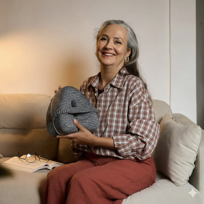 Woman sitting on a couch holding a gray bag, smiling.