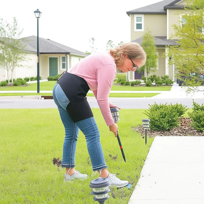 Person using a tool to adjust or install outdoor lights on a lawn.
